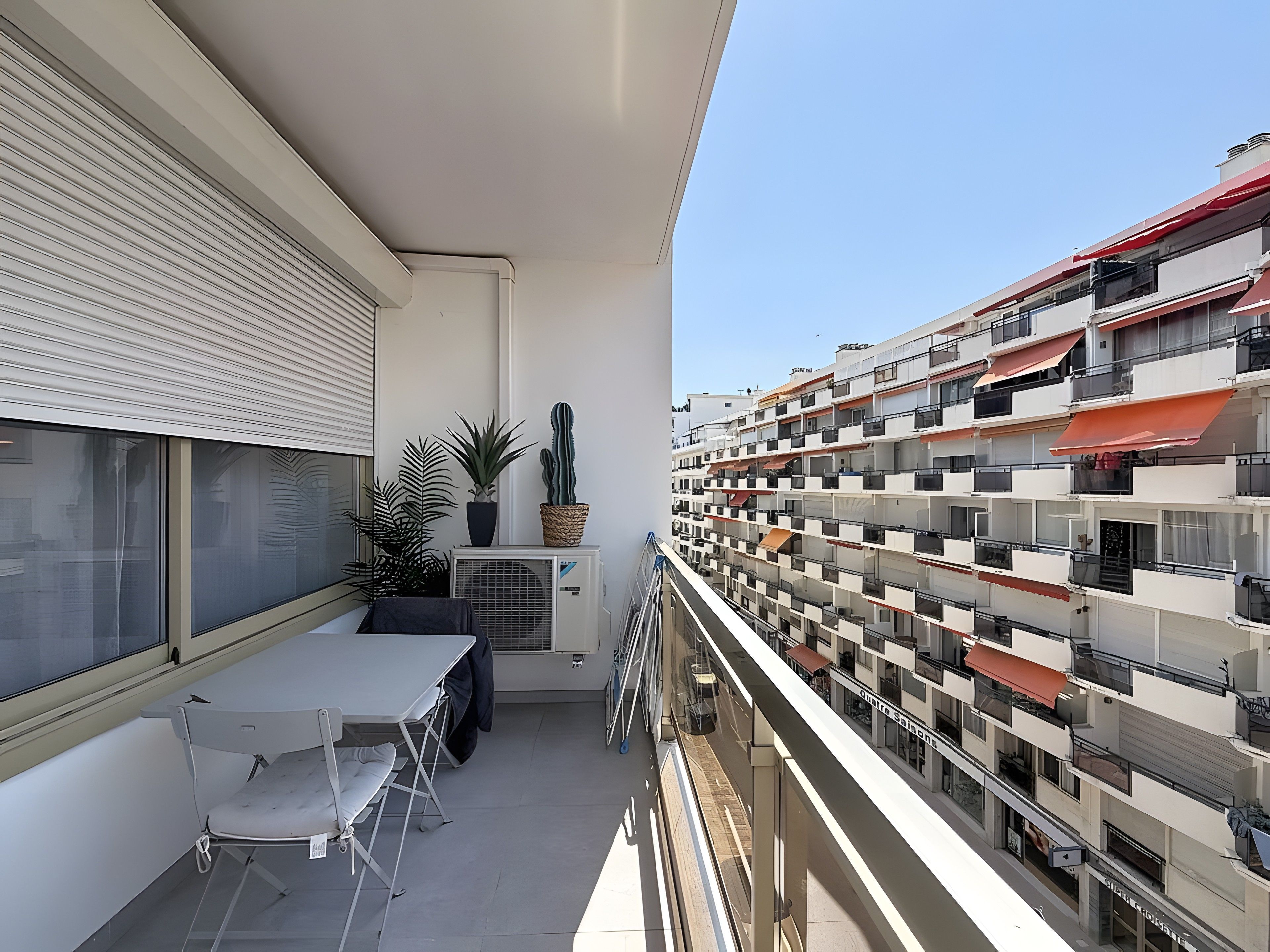 A balcony with a table, chairs, and potted plants.
