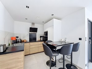 A modern kitchen with a central island, bar stools, and a dining table. - Apartment 'Appartement 2 Pièces Cannes' with Sea View, Wi-Fi and Air Conditioning (Cannes)