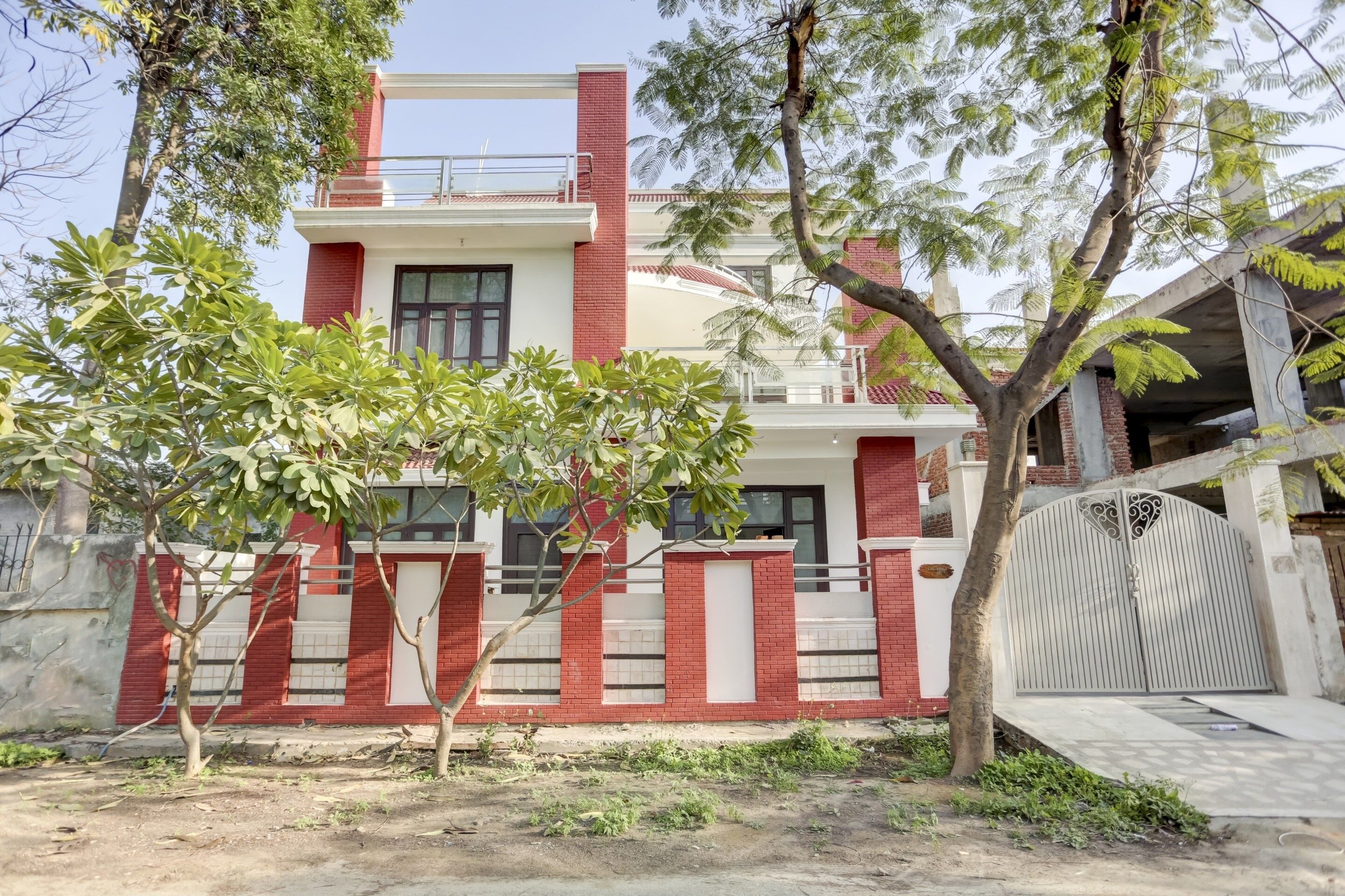A two-story house with a red brick facade, white trim, and a gated entrance.