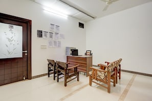 Une salle de conférence équipée d’un tableau blanc, de documents, d’une imprimante et de chaises en bois.