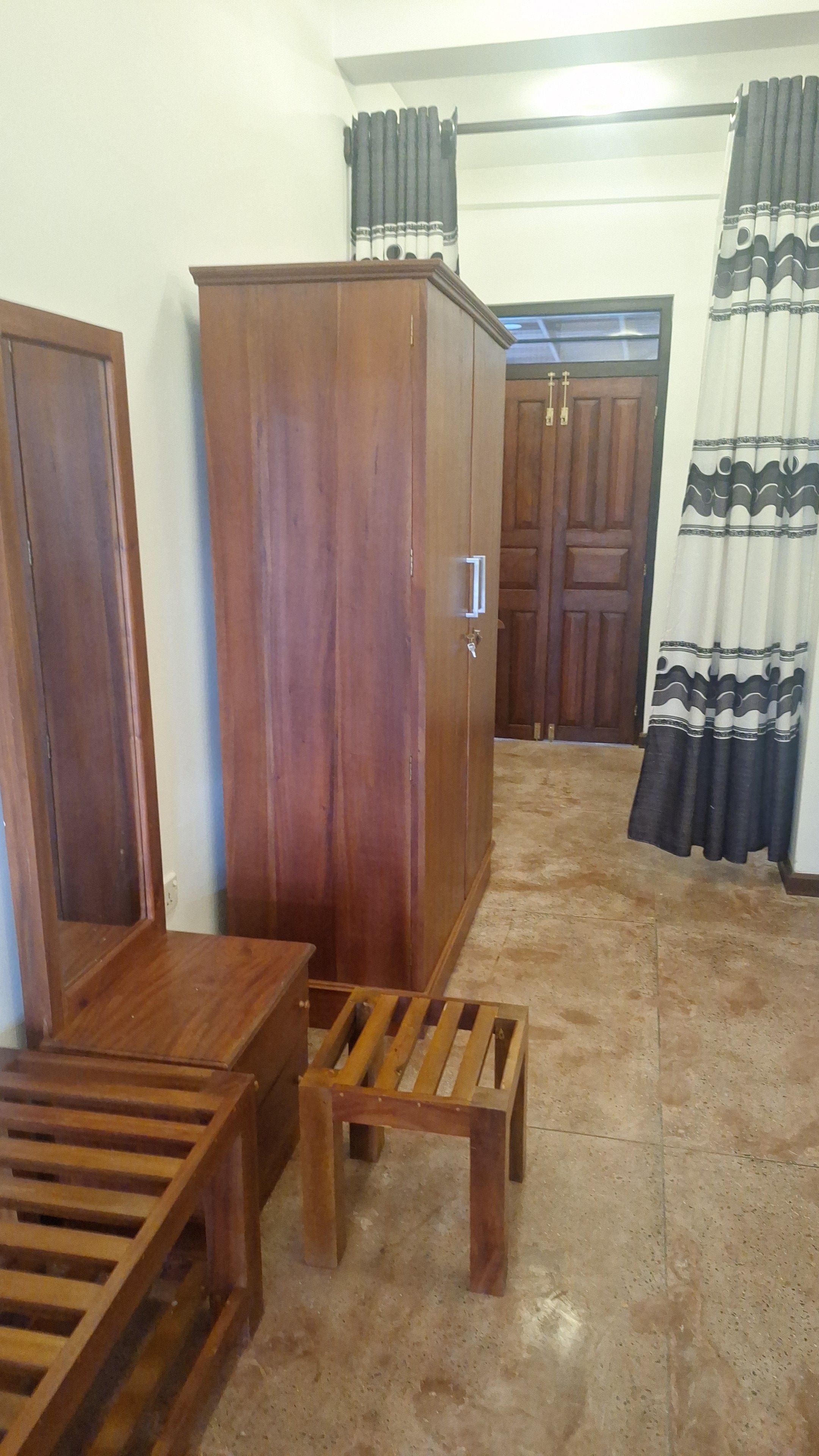 A room with a wooden wardrobe, a wooden bench, and a small wooden stool.