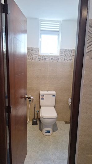 Un baño con inodoro, ventana y zona de ducha.