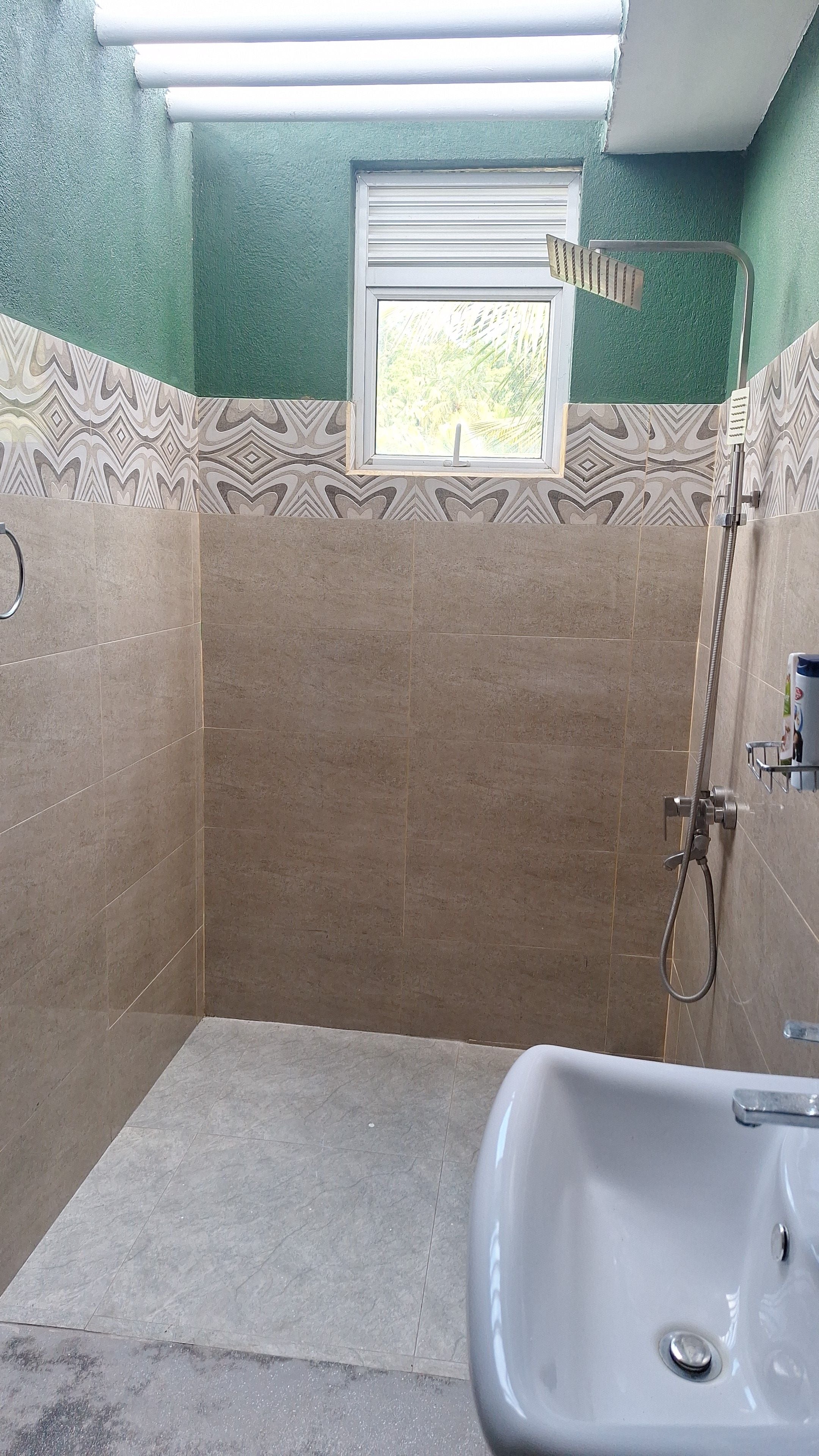 Un baño con ducha, lavamanos y ventana.