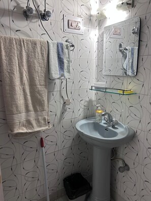 Un baño con lavamanos blanco, espejo, toallero y cubo de basura.