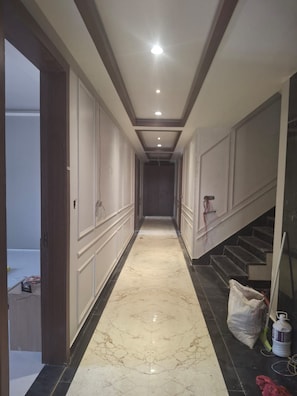 A hallway with a marble floor, a staircase on the right, and a door on the left. - Ayodhya Blossom (Ayodhya)