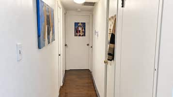 A hallway with wooden flooring, white walls, and doors on both sides.