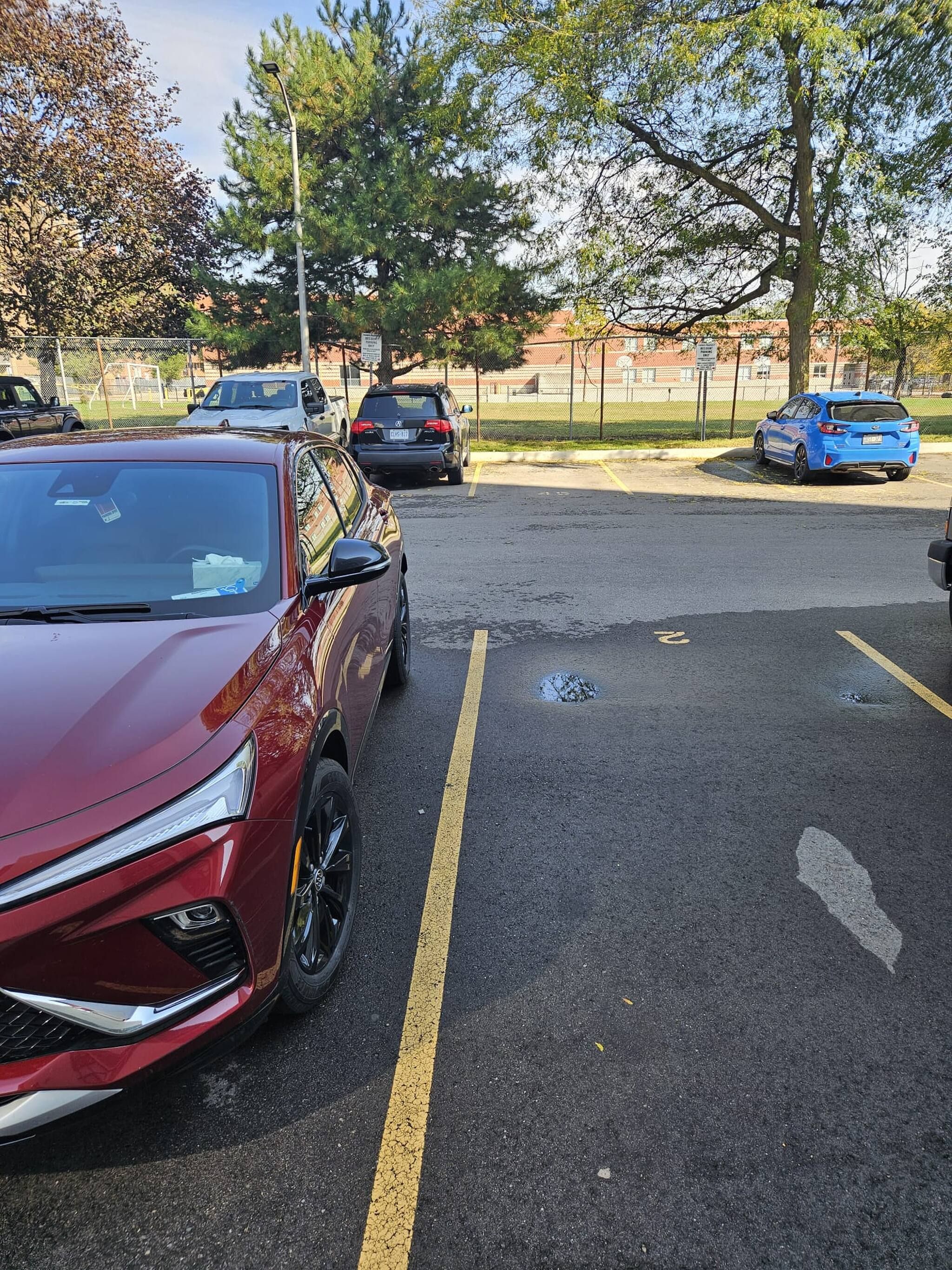 A parking lot with multiple cars, including a red SUV and a blue hatchback.
