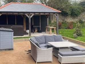 A covered outdoor seating area with a patio table and a sofa. - The Little Willow Barn (Kent)