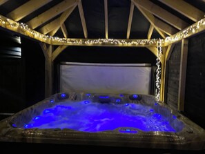 A hot tub with blue lighting inside a wooden structure. - The Little Willow Barn (Kent)