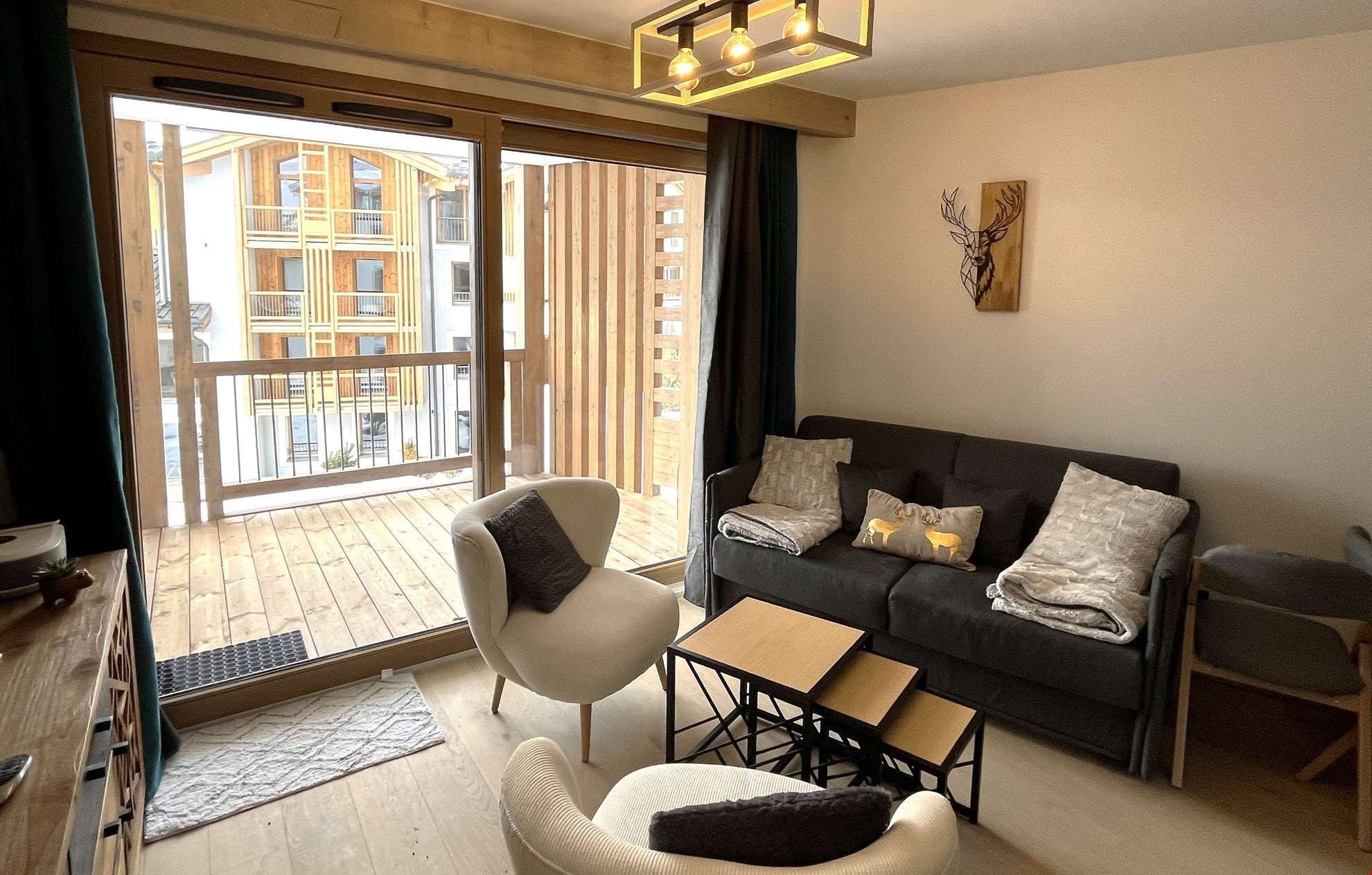 Una sala de estar moderna con sofá, sillones, una mesa de centro y un balcón con piso de madera.