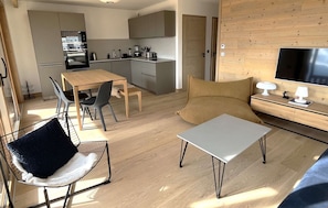A modern living space with a dining area, kitchen, and a TV. - R Sidence Phoenix B13 3p6p (Huez)