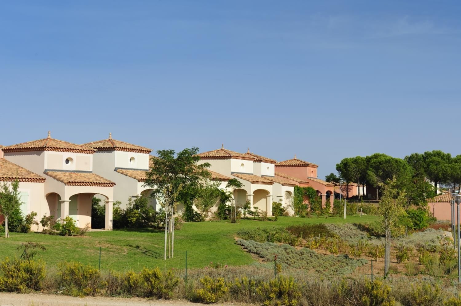 A series of buildings with arched doorways and tiled roofs, surrounded by a well-maintained grassy area.