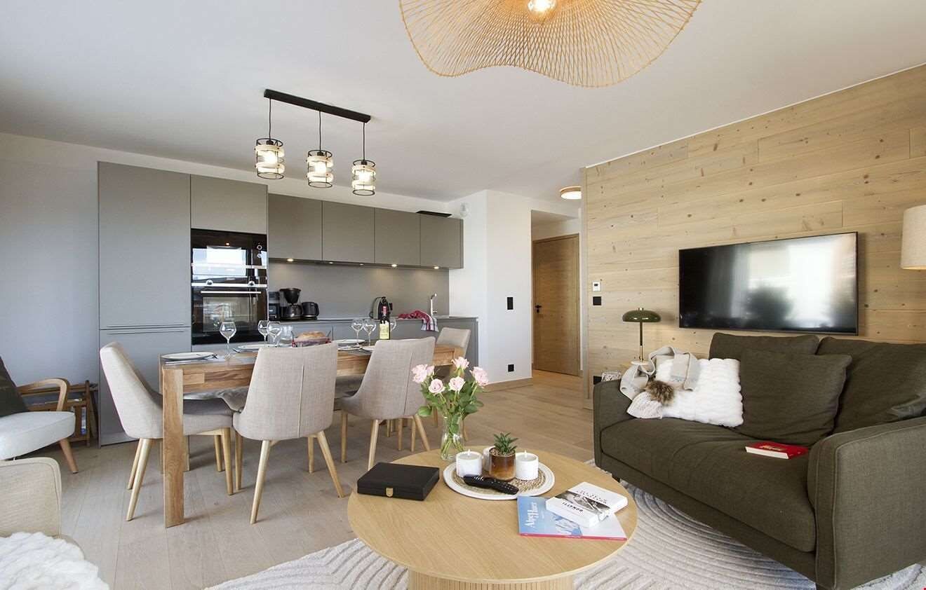 Una sala de estar moderna con un sofá, una mesa de centro y un televisor de pantalla plana montado en la pared.