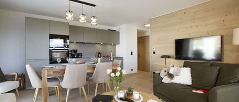 A modern living room with a sofa, coffee table, and a flat-screen TV mounted on the wall.