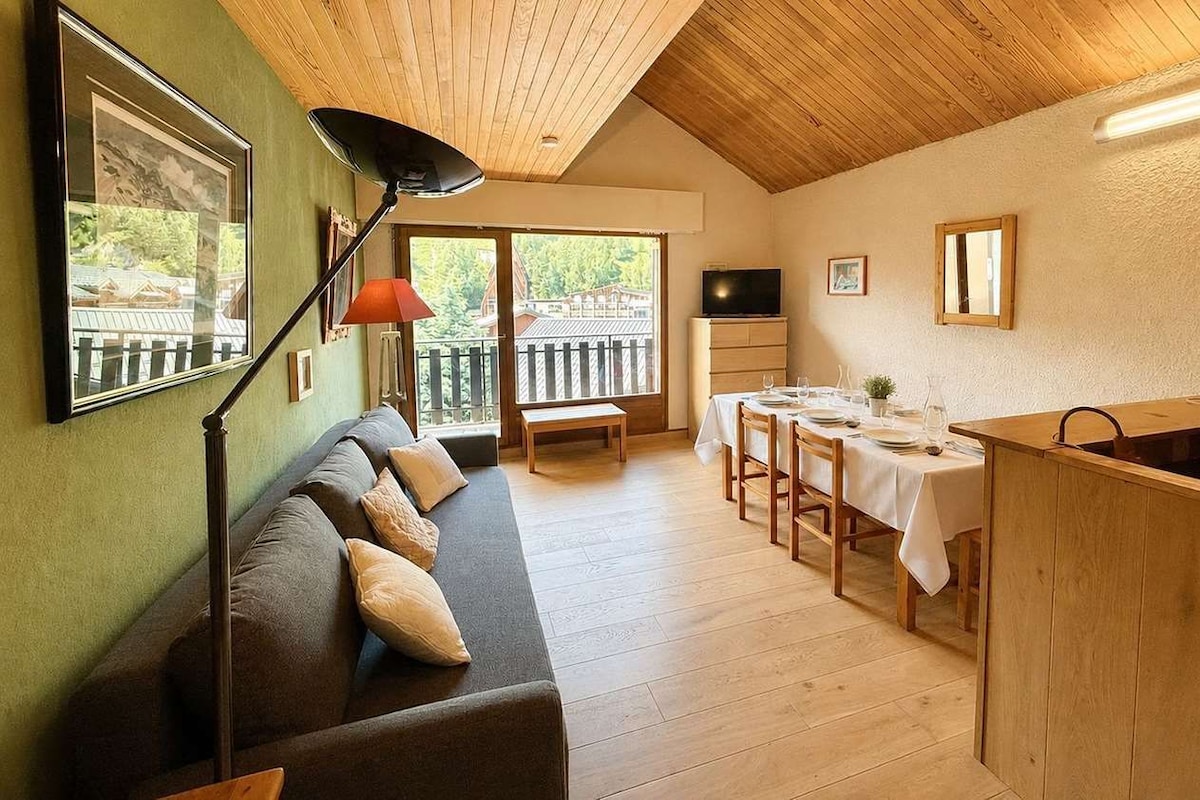 Una sala acogedora con un sofá, una mesa de comedor para cuatro y una encimera de cocina.