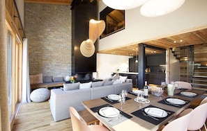 A modern living space with a dining area, a stone wall, and a fireplace. - Chalet des 3 Ours 11p 3 Levels (Les Deux Alpes)