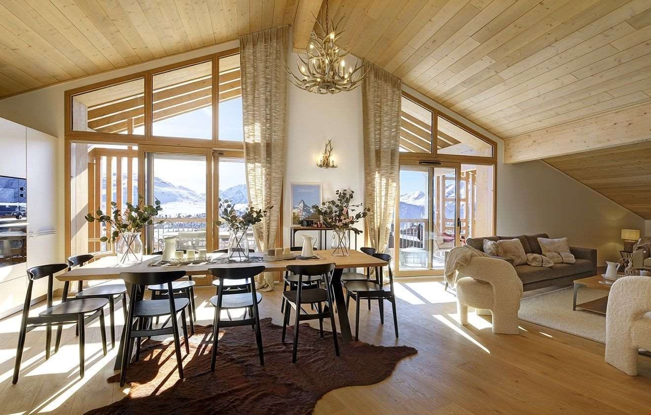 Un amplio salón con techo alto, ventanas grandes y vistas a las montañas.