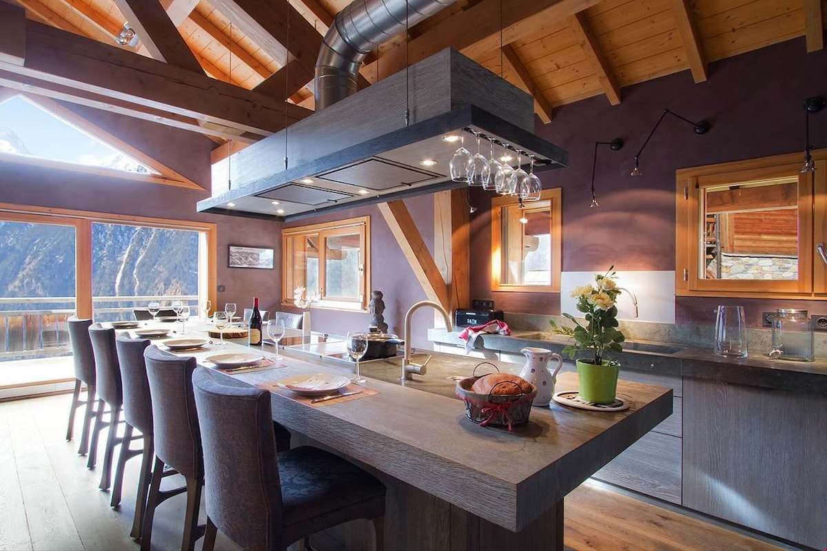 Una cocina moderna con una isla central, vigas de madera y vistas a las montañas.