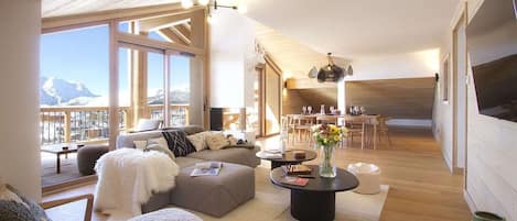 A spacious living area with a large window, a cozy seating arrangement, and a dining area.