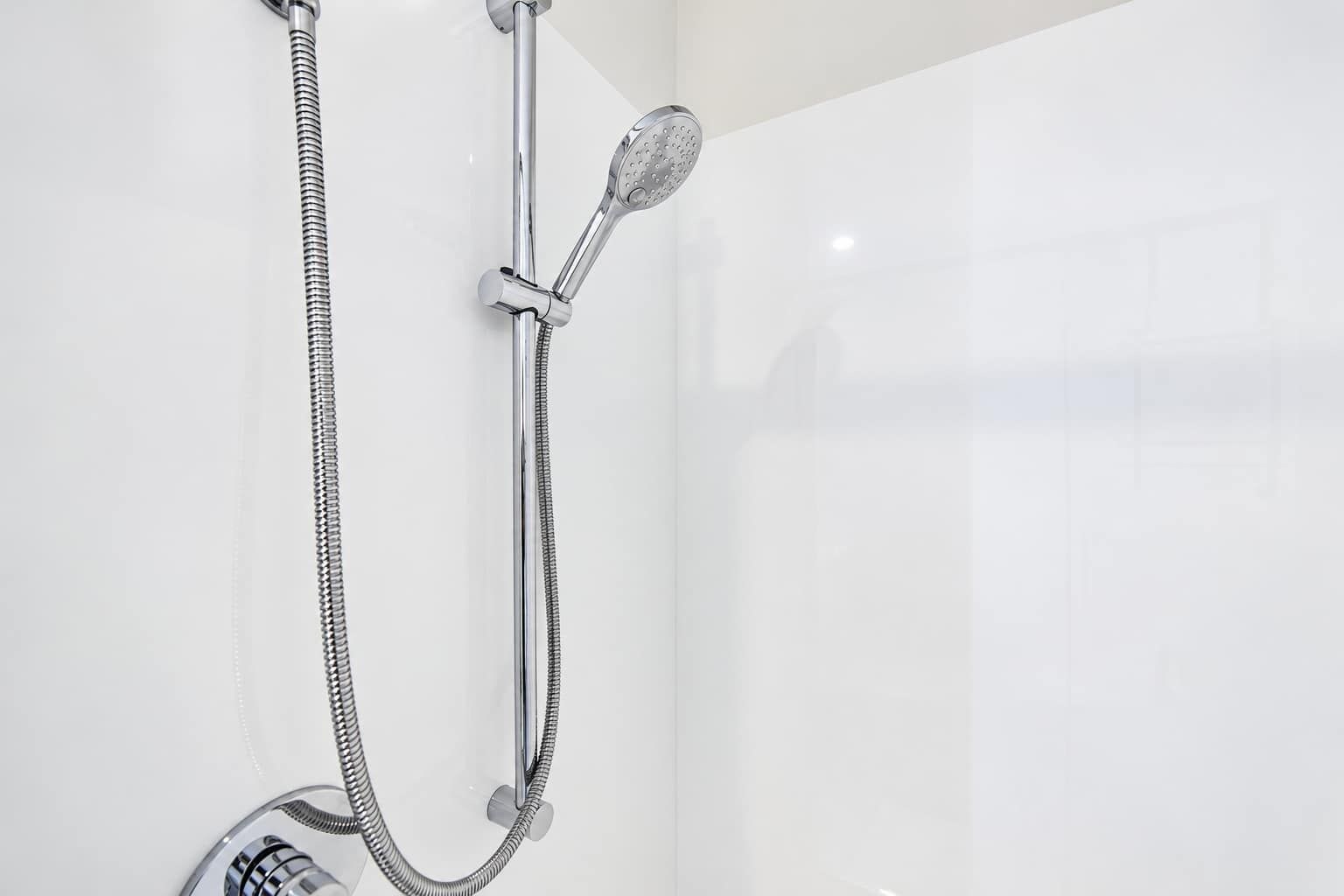 Rinse off beneath the handheld showerhead, mounted on an adjustable rail with a flexible hose and mixer control.