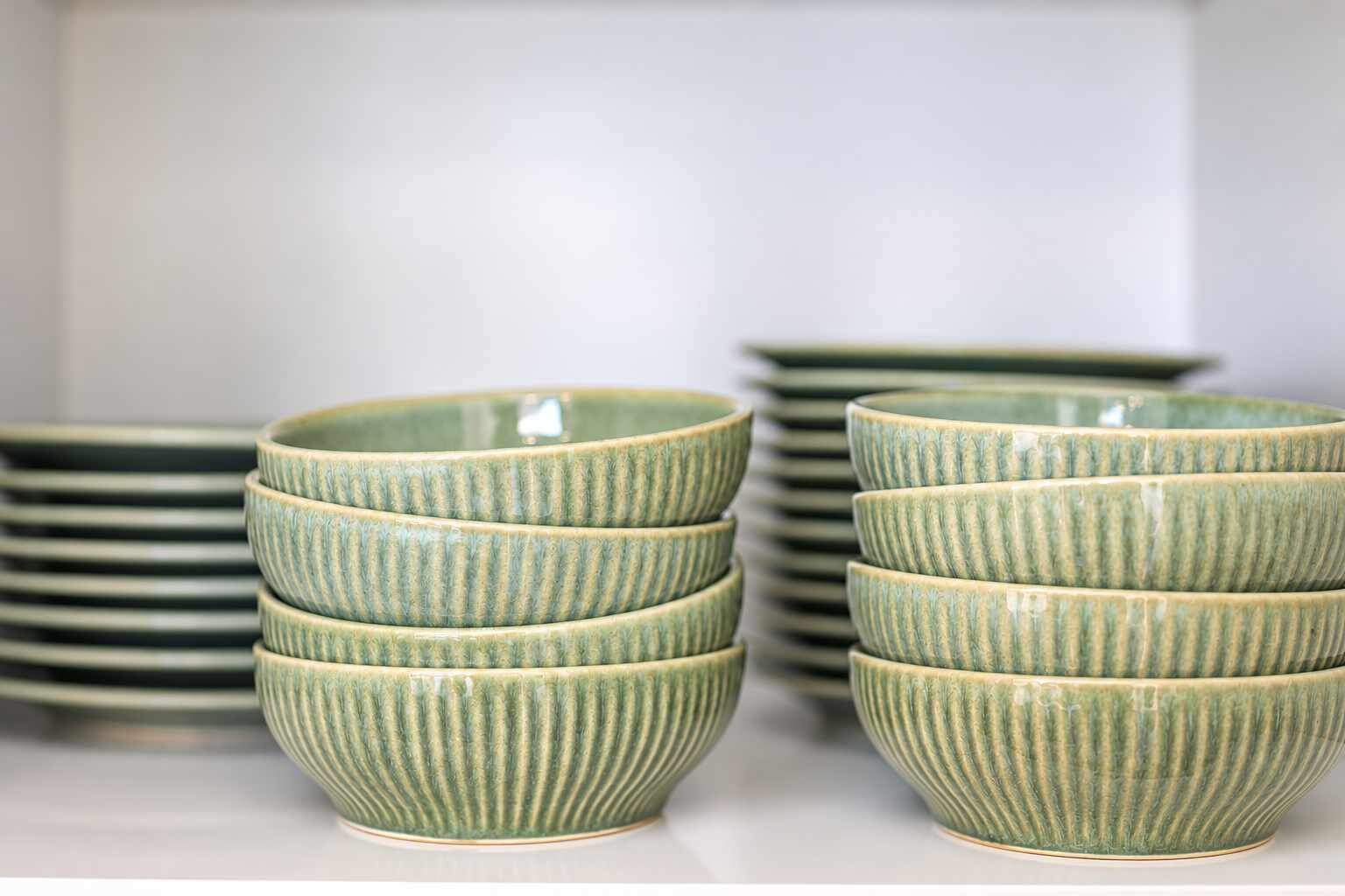 Serve meals with the kitchen’s collection of plates and bowls, neatly stacked inside the cupboard for easy access.