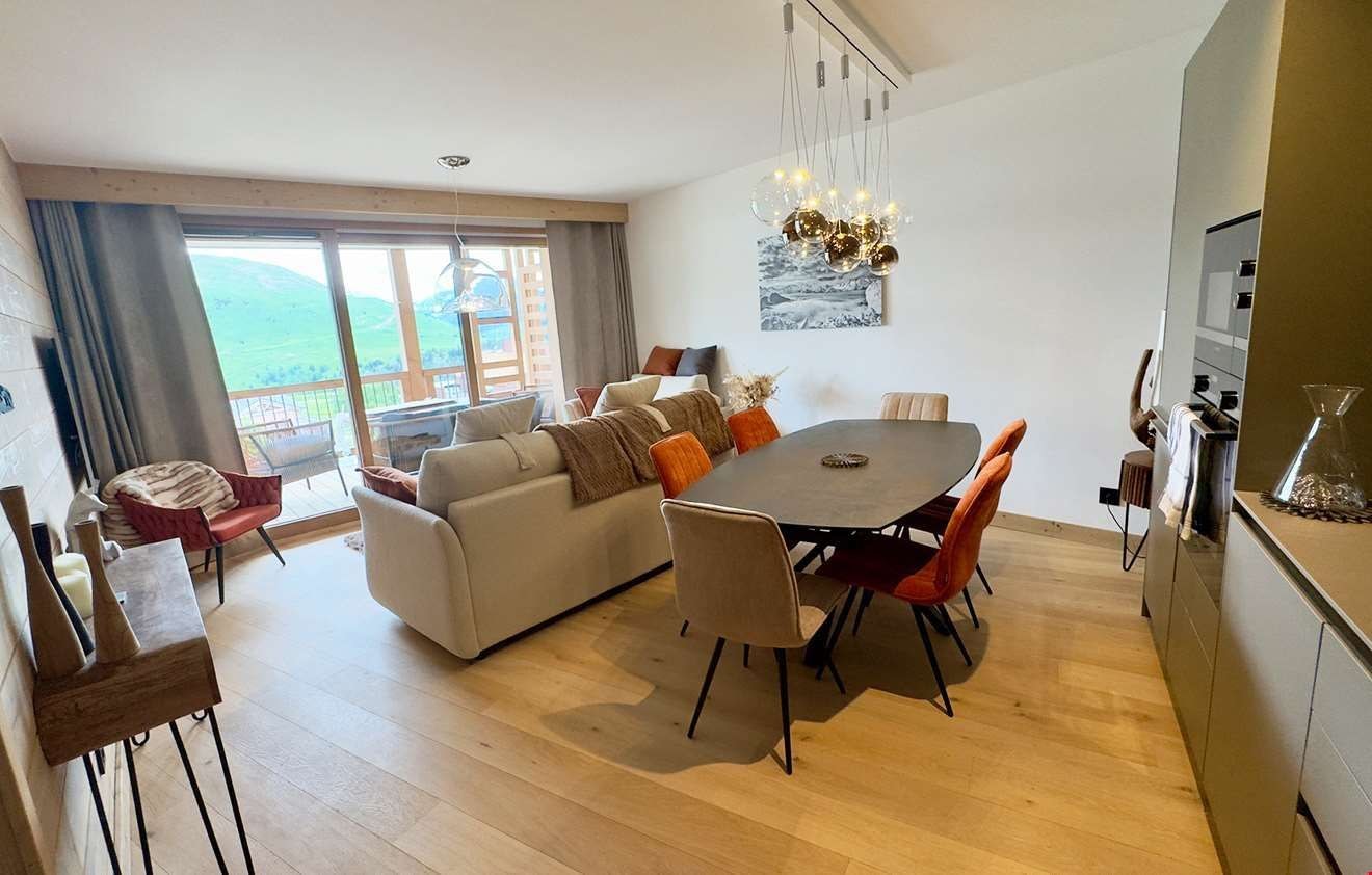 A modern living room with a dining area, large windows, and a view of the outdoors.