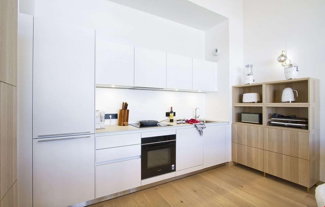 Eine moderne Küche mit weißen Schränken, einem eingebauten Backofen und einer Holzkonsolenwand.