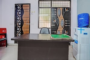 A room with a desk, chairs, a window with bars, and a door with a floral design. - Hotel O Krishna Residency (Noida)