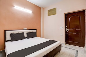 Une chambre à coucher avec un lit, une porte en bois et un luminaire fixé au mur.