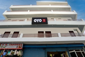 A hotel named OYO with a signboard, a balcony, and a storefront with a sign for V. K. Traders.