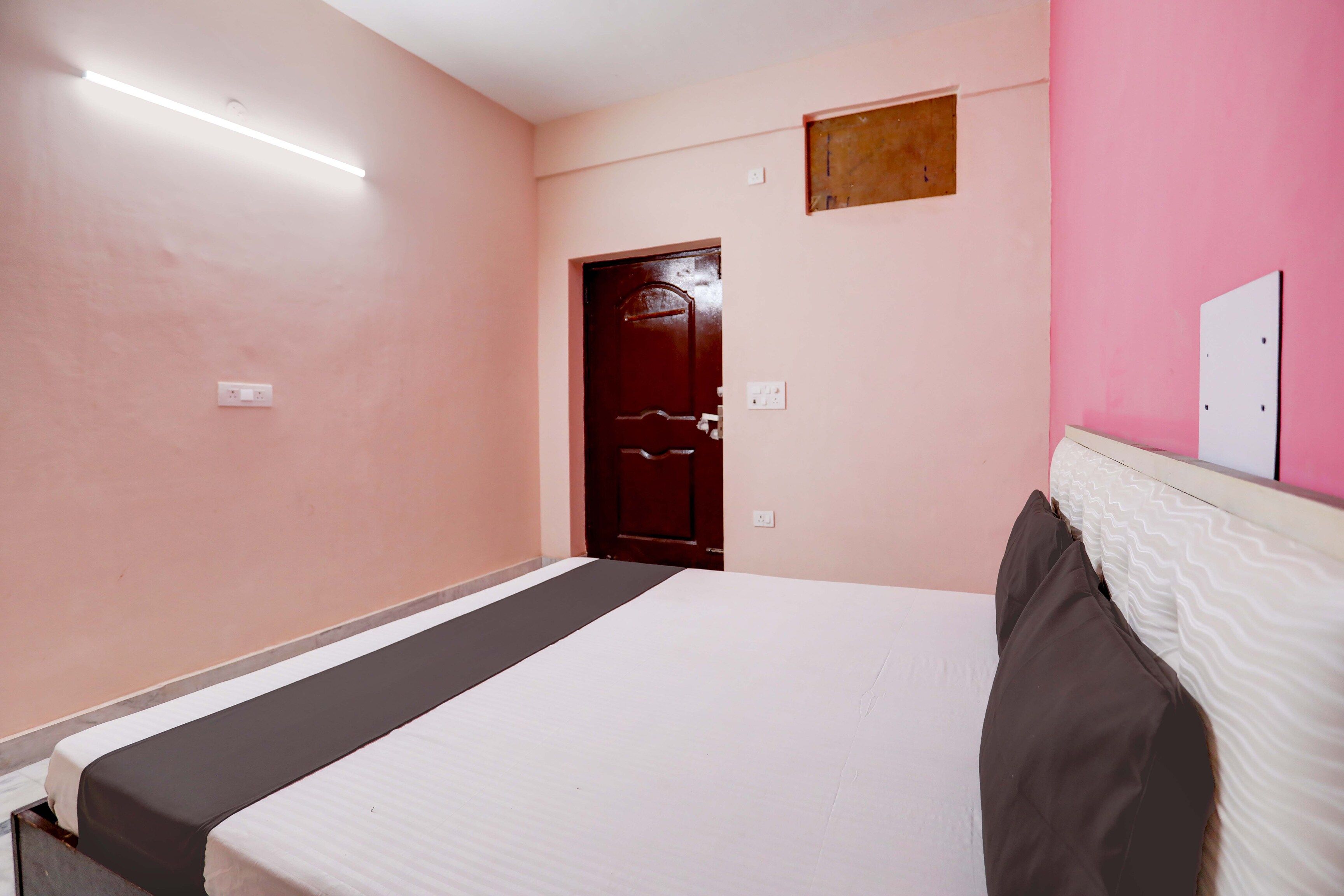 A bedroom with a bed, a door, and a light fixture.