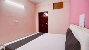 A bedroom with a bed, a door, and a light fixture.