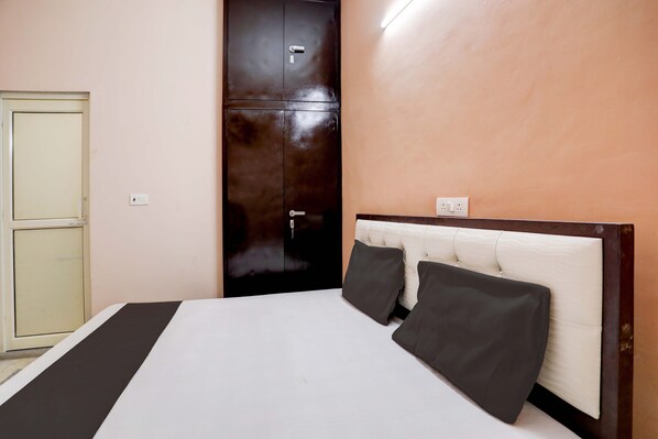 A hotel room with a bed, a wardrobe, and a wall socket.