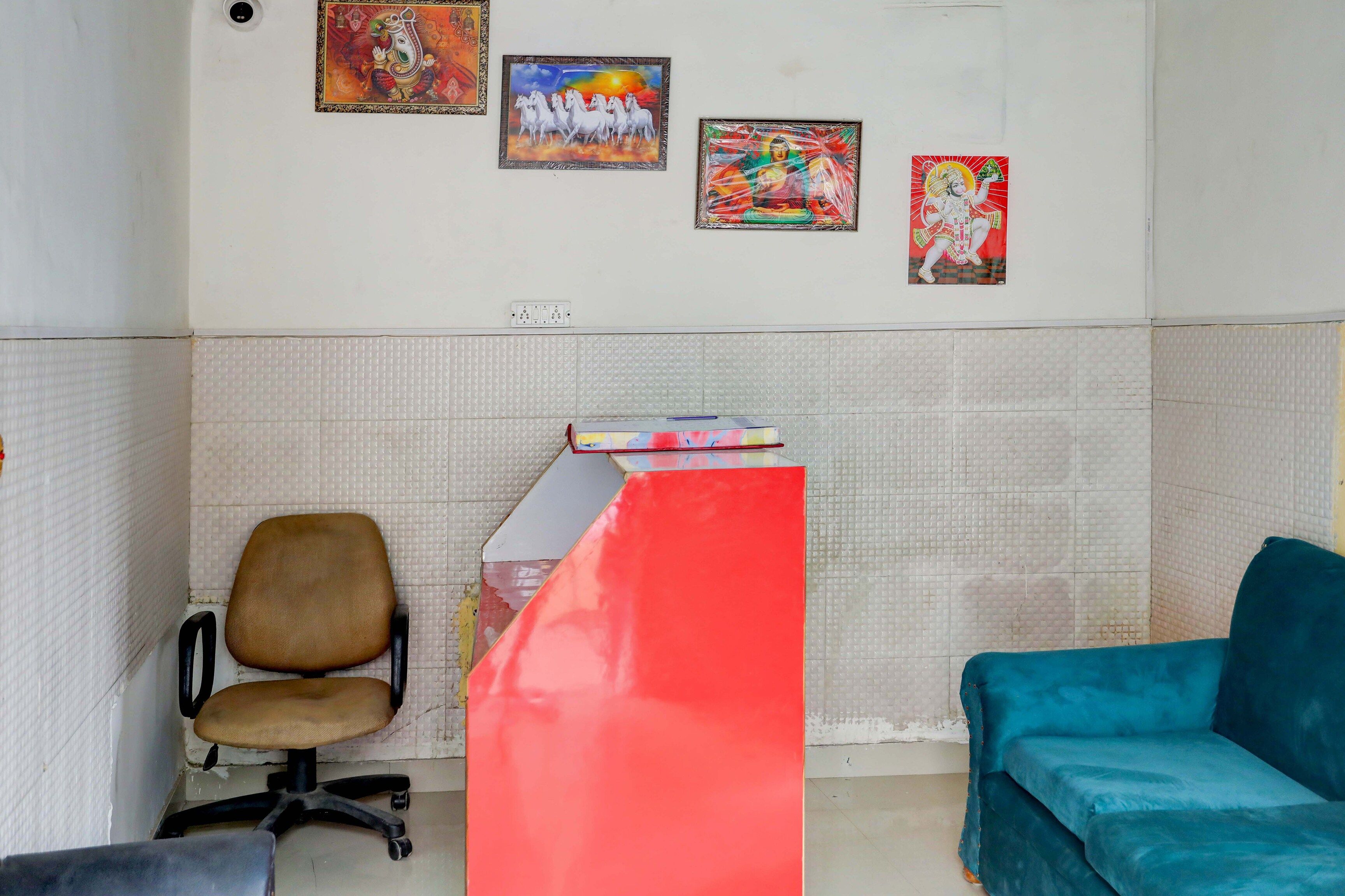 Une pièce comprenant un bureau, une chaise, un canapé et quatre œuvres d’art encadrées accrochées au mur.