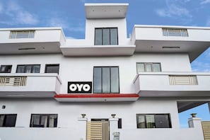 Un edificio moderno con un llamativo letrero 'OYO', varios balcones y una entrada con portón.