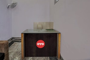 Un mostrador de recepción con un logotipo, una pared con azulejos y una ventana.