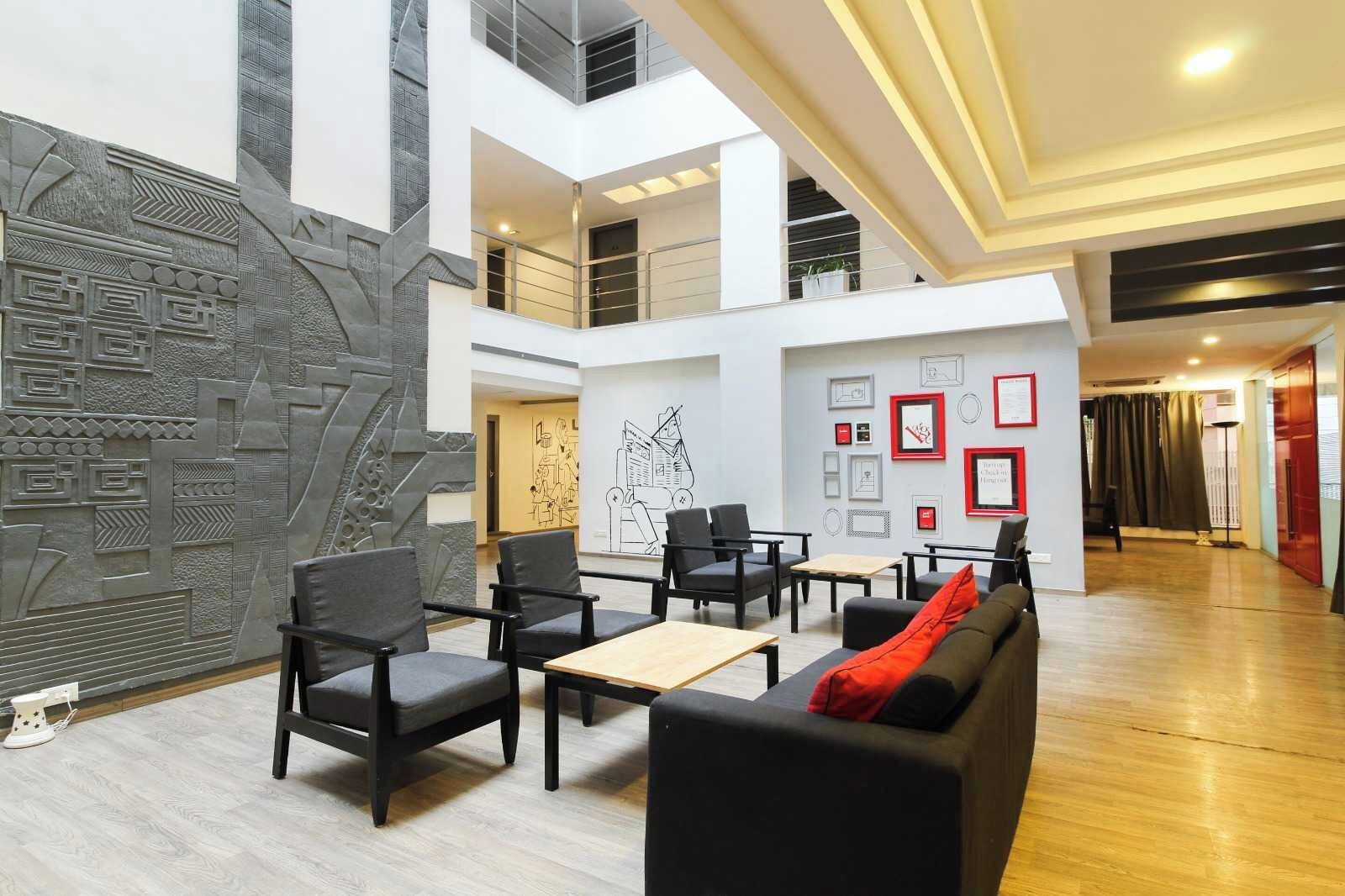 A spacious lobby with a high ceiling, modern furniture, and a decorative wall.