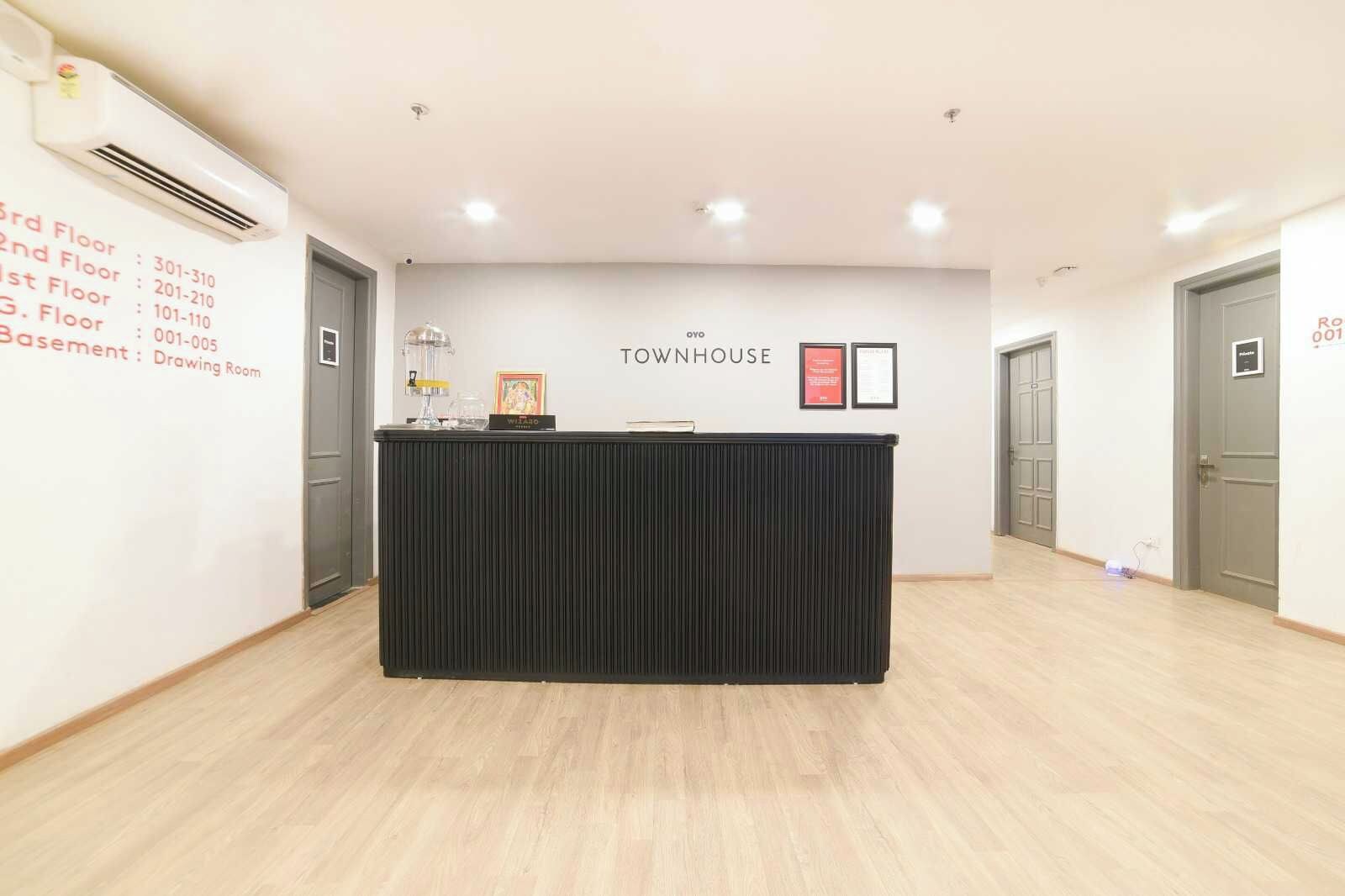 A reception desk with a black backdrop, a wall-mounted air conditioner, and a sign indicating the location as 'TOWNHOUSE.'