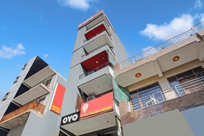 Een hotel met meerdere balkons, een opvallend 'OYO' bord en een helderblauwe lucht op de achtergrond.