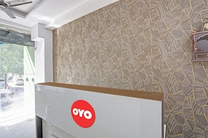 Une pièce avec un mur orné d’un motif, un ventilateur de plafond et un grand tableau blanc sur lequel est apposé un logo.