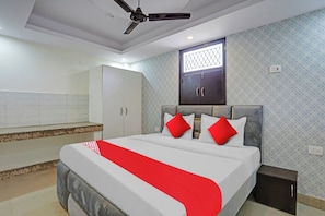 Une chambre à coucher avec un lit, une armoire, un ventilateur de plafond et une fenêtre.