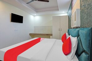 Een hotelkamer met een bed, een televisie, een kledingkast en een airconditioner.