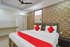 Une chambre d’hôtel avec un lit, une armoire, un ventilateur de plafond et un mur décoré de motifs.