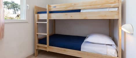 Un letto a castello con un letto inferiore e una scala, una finestra con tende e una lampada da comodino.