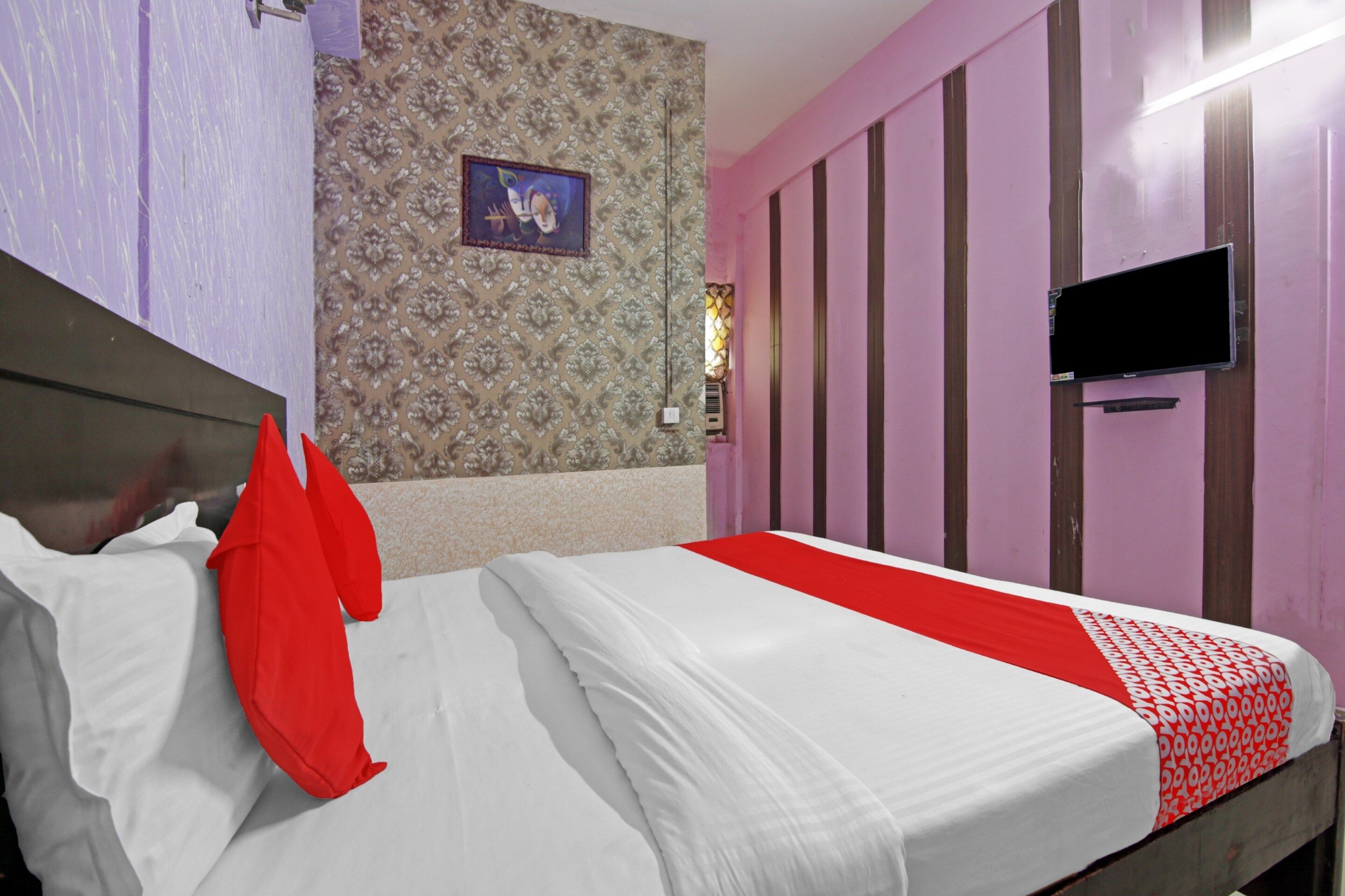 Une chambre avec un lit, un téléviseur fixé au mur et un papier peint à motifs.