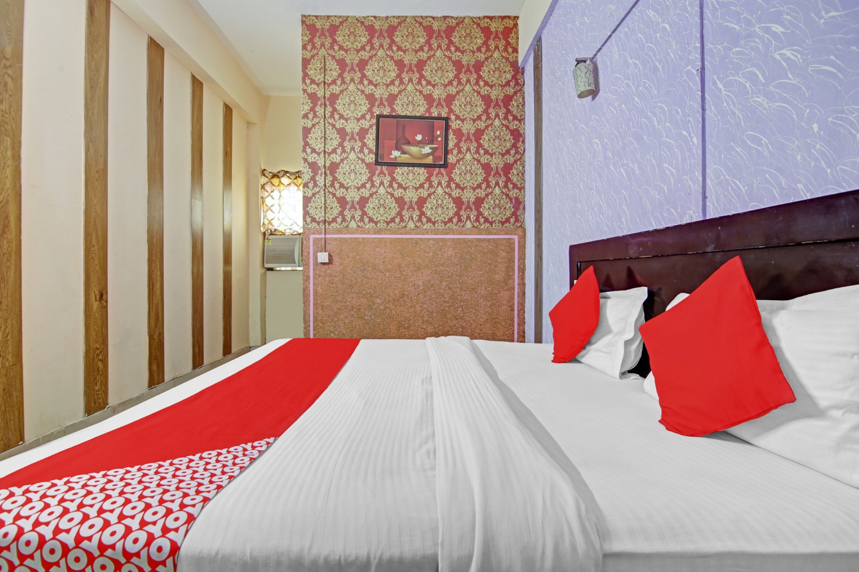 Une chambre d’hôtel avec un lit, un mur décoré d’un motif rouge et blanc, et une porte en bois.