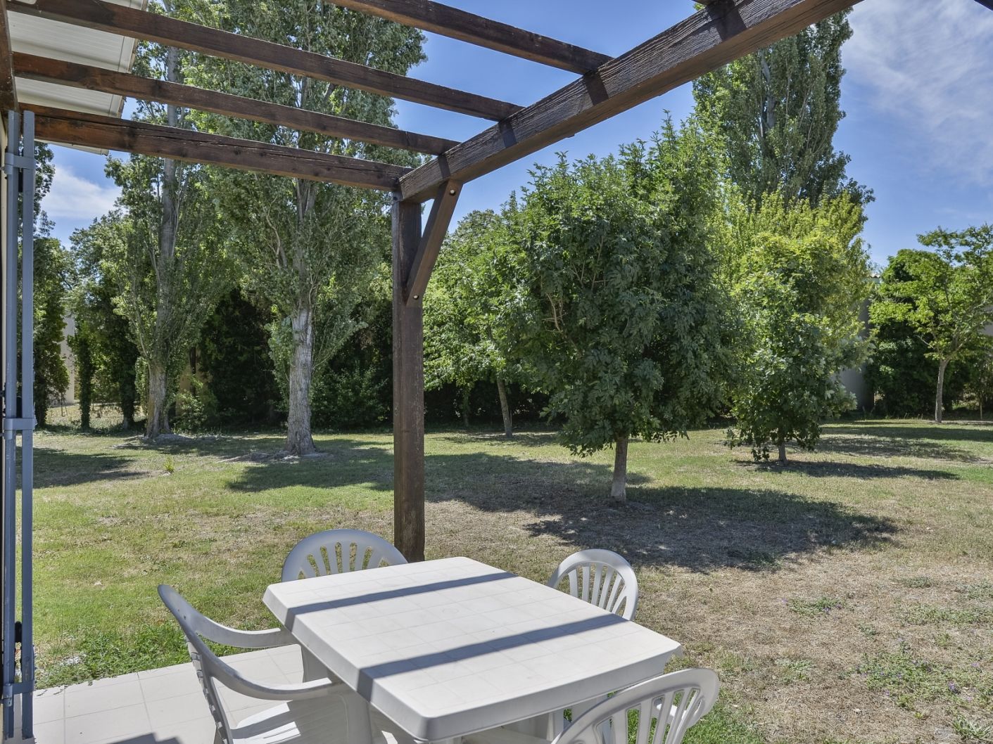 An outdoor patio with a table and chairs, surrounded by trees.