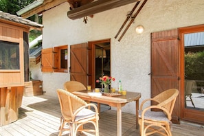 A wooden deck with a table and chairs, a wooden door, and a window.