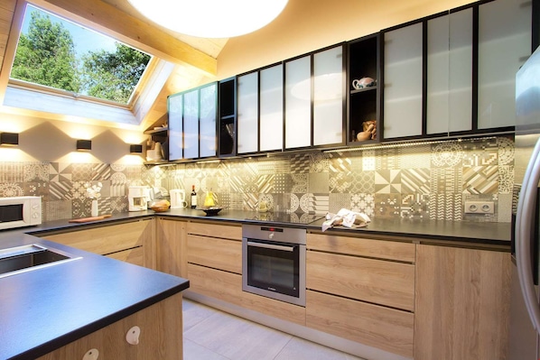 A modern kitchen with wooden cabinets, a built-in oven, and a skylight.
