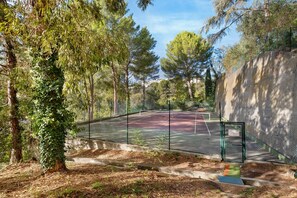 A tennis court surrounded by trees and a stone wall. - Apartment 'Studio Nice' with Shared Pool, Wi-Fi and Air Conditioning (Nice)